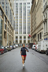 A young asian girls runs through the wet city streets of Boston. - AURF04596