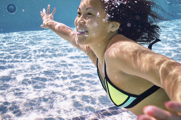Eine junge asiatische Amerikanerin genießt einen Sommertag am Pool. - AURF04604
