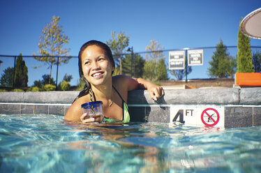 Eine junge asiatische Amerikanerin genießt einen Sommertag am Pool. - AURF04605