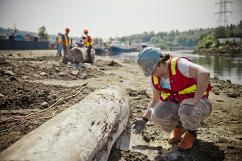 Eine Frau prüft, ob der Beton auf einer Baustelle zur Wiederherstellung von Flussmündungen trocken ist. - AURF04636