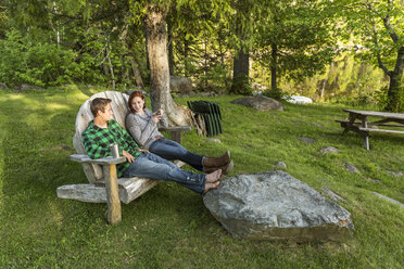 Ein junges Paar genießt einen Abend in einem Adirondack-Stuhl in einer Lodge in der Nähe von Greenville, Maine - AURF04658