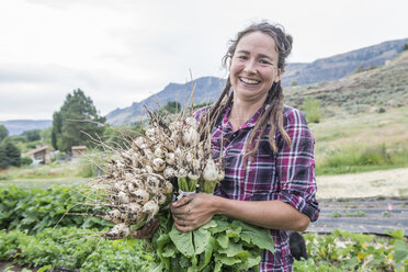 A woman holds freshly harvested radishes on an organic farm in Washington State. - AURF04678