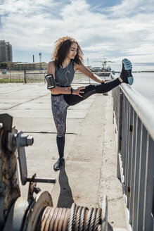Junge sportliche Frau beim Stretching am Flussufer - VPIF00780
