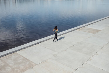 Junge sportliche Frau beim Laufen am Flussufer - VPIF00794