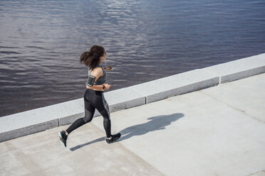 Junge sportliche Frau beim Laufen am Flussufer - VPIF00795