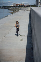 Junge sportliche Frau beim Laufen am Flussufer - VPIF00800