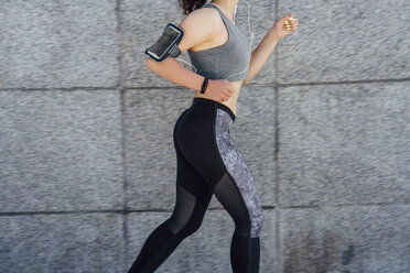 Partial view of young athletic woman running along a wall - VPIF00807