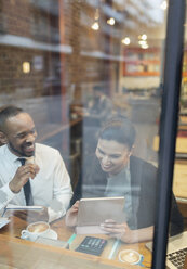 Smiling business people using digital tablet, working at cafe window - CAIF21988