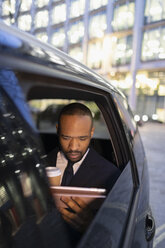 Geschäftsmann trinkt Kaffee und benutzt ein digitales Tablet in einem Crowdsourced Taxi - CAIF21997