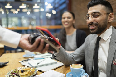 Businessman paying with smart phone contactless payment in cafe - CAIF22000