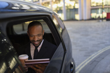 Geschäftsmann trinkt Kaffee und benutzt ein digitales Tablet in einem Crowdsourced Taxi - CAIF22001