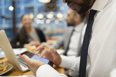 Nahaufnahme eines Geschäftsmannes, der ein Smartphone in einem Café benutzt - CAIF22002