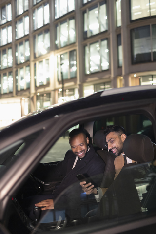 Geschäftsmann zeigt dem Fahrer im Crowdsourced Taxi sein Smartphone, lizenzfreies Stockfoto