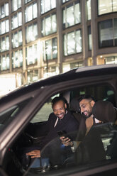 Geschäftsmann zeigt dem Fahrer im Crowdsourced Taxi sein Smartphone - CAIF22012