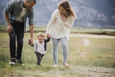 Eltern gehen mit ihrem kleinen Sohn in einem ländlichen Gebiet spazieren - CAIF22034