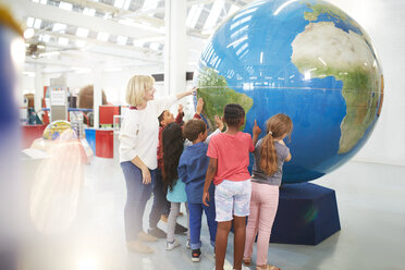 Teacher and students touching large globe in science center - CAIF22037