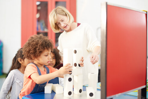 Lehrerin und neugierige Schüler stapeln große Dominosteine im Wissenschaftszentrum - CAIF22074