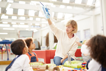 Neugierige Kinder beobachten Lehrer mit Spielzeugflugzeug im Wissenschaftszentrum - CAIF22085