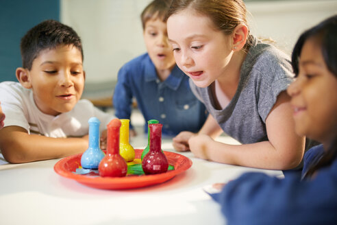 Neugierige Kinder beobachten mehrfarbigen Schaum in Bechern - CAIF22097