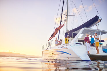 Young woman diving off catamaran into ocean - CAIF22121