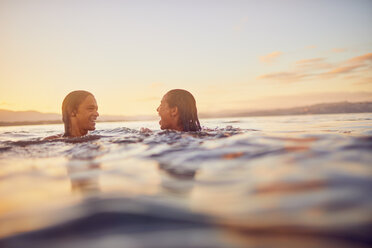 Junges Paar schwimmt bei Sonnenuntergang im Meer - CAIF22122