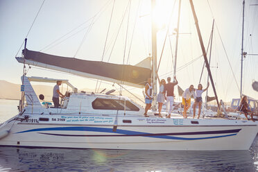 Portrait friends waving on catamaran in sunny harbor - CAIF22127