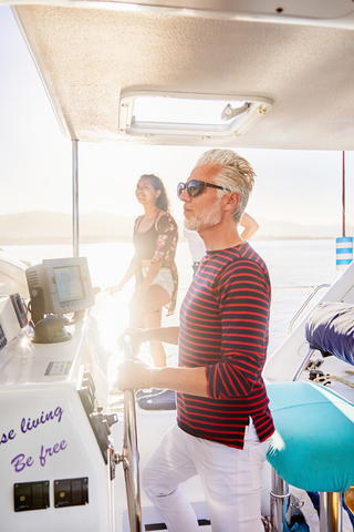 Mann am Ruder auf sonnigem Boot, lizenzfreies Stockfoto