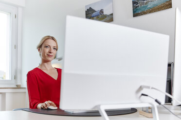 Porträt einer jungen Frau, die am Schreibtisch im Büro am Computer arbeitet - RHF02113