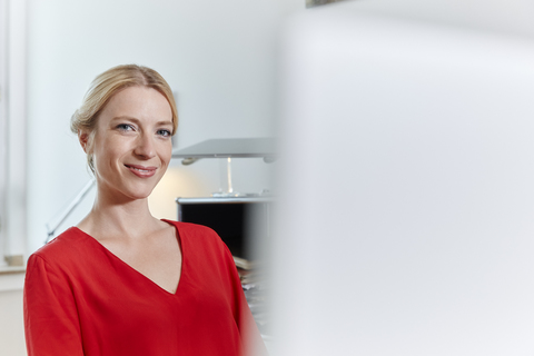 Porträt einer lächelnden jungen Frau im Büro, lizenzfreies Stockfoto
