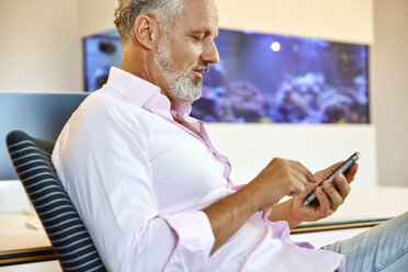 Businessman sitting in office using cell phone - RHF02137