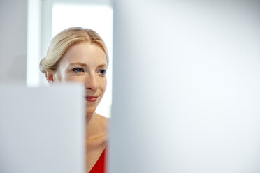 Porträt einer lächelnden jungen Frau bei der Arbeit am Computer - RHF02144