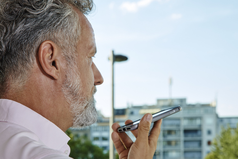 Nahaufnahme eines reifen Mannes, der im Freien ein Smartphone benutzt, lizenzfreies Stockfoto