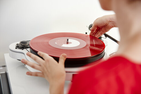 Frau legt rote Schallplatte auf Plattenspieler - RHF02171