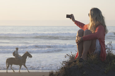 Reife Frau fotografiert chilenischen Cowboy an der Strandpromenade - AURF04718