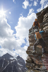Bergführer hilft einer Bergsteigerin beim Aufstieg über die Felswand - AURF04721