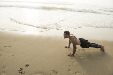 Muskulöser Mann, der allein am Sandstrand trainiert, Hampton, New Hampshire, USA - AURF04743