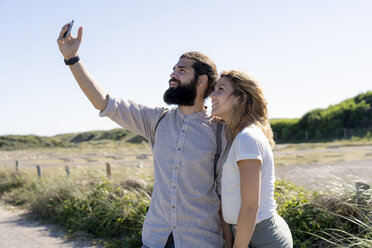 Junges Paar macht Smartphone-Selfies am Strand - HHLMF00398