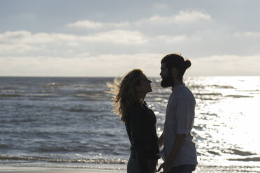 Young couple looking at each other, standing at the sea - HHLMF00441