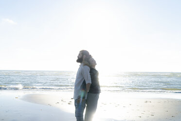 Young couple standing back to back at the sea - HHLMF00470