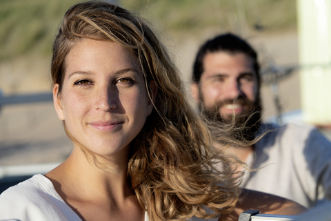 Pärchen am Strand, Frau schaut in die Kamera, lizenzfreies Stockfoto