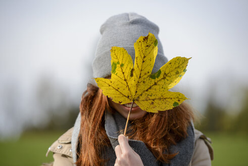 Teenager-Mädchen versteckt sich hinter Herbstblatt - LBF02043