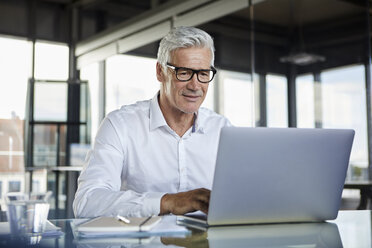 Geschäftsmann, der im Büro arbeitet und einen Laptop benutzt - RBF06575