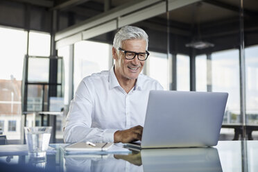 Businessman working in office, using laptop - RBF06576