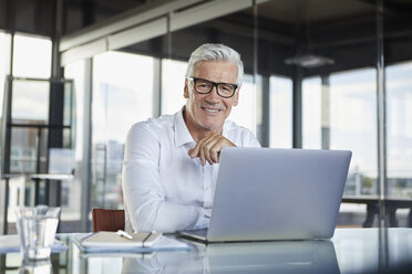 Geschäftsmann, der im Büro arbeitet und einen Laptop benutzt - RBF06581