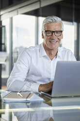 Geschäftsmann, der im Büro arbeitet und einen Laptop benutzt - RBF06582