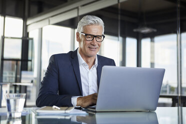 Geschäftsmann, der im Büro arbeitet und einen Laptop benutzt - RBF06583