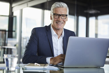 Geschäftsmann, der im Büro arbeitet und einen Laptop benutzt - RBF06584