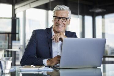 Geschäftsmann, der im Büro arbeitet und einen Laptop benutzt - RBF06585