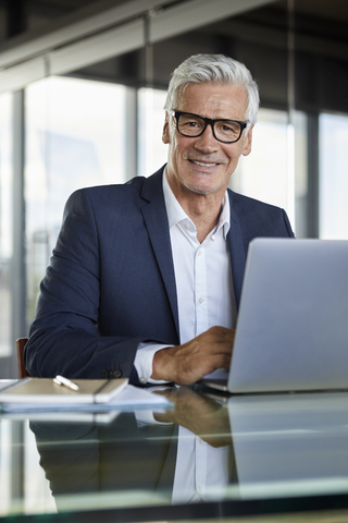 Geschäftsmann, der im Büro arbeitet und einen Laptop benutzt, lizenzfreies Stockfoto