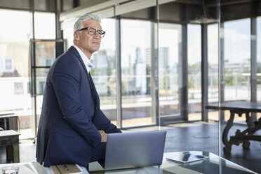 Successful manager sitting on desk, thinking - RBF06595